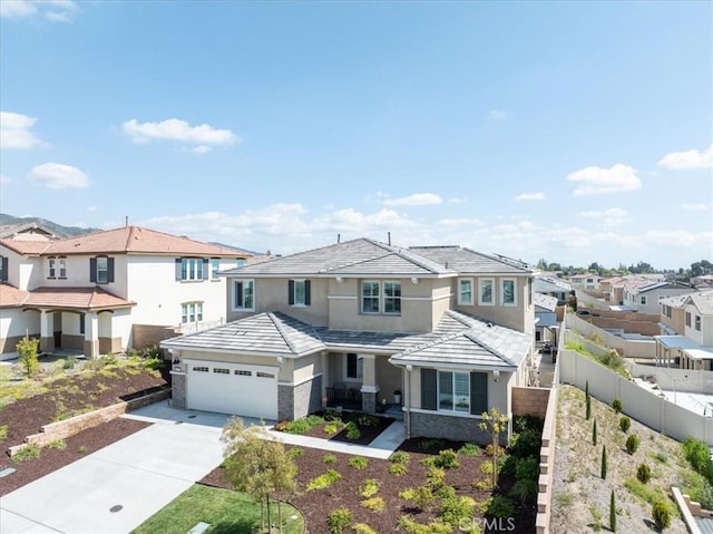 view of front of house with driveway, a tiled roof, fence, and a residential view