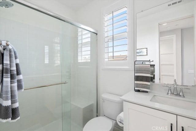 full bath featuring toilet, a stall shower, vanity, and visible vents