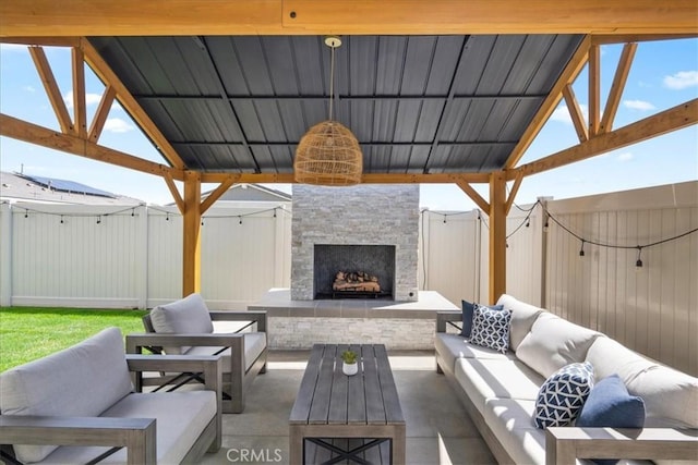 view of patio / terrace with an outdoor living space with a fireplace, fence, and a gazebo