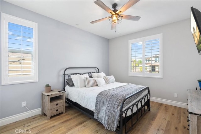 bedroom featuring light wood finished floors, ceiling fan, and baseboards