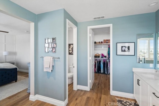 full bathroom with toilet, wood finished floors, visible vents, and baseboards