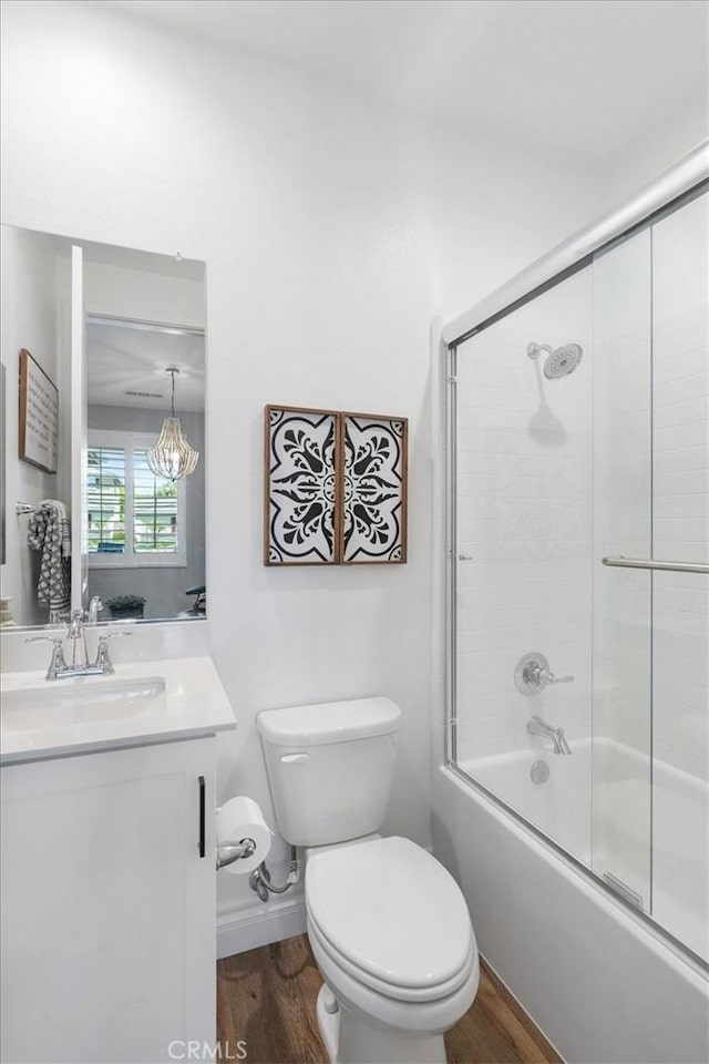 full bath featuring baseboards, bath / shower combo with glass door, toilet, wood finished floors, and vanity