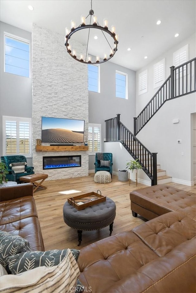 living area with a healthy amount of sunlight, wood finished floors, and a stone fireplace