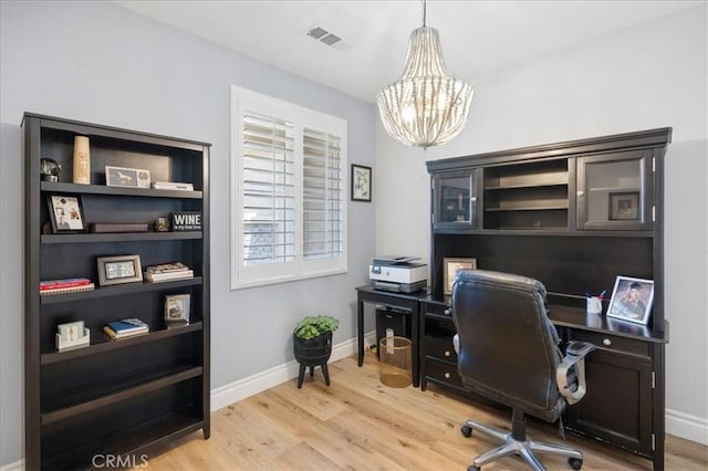 office with light wood finished floors, visible vents, baseboards, and an inviting chandelier