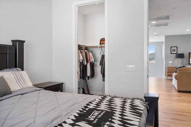 bedroom with recessed lighting, wood finished floors, visible vents, a spacious closet, and a closet