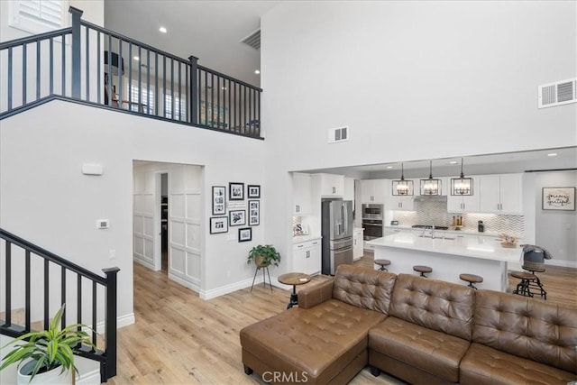 living room with light wood-type flooring, visible vents, and baseboards