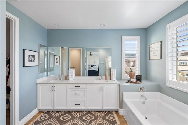 ensuite bathroom with a bath, plenty of natural light, and a sink