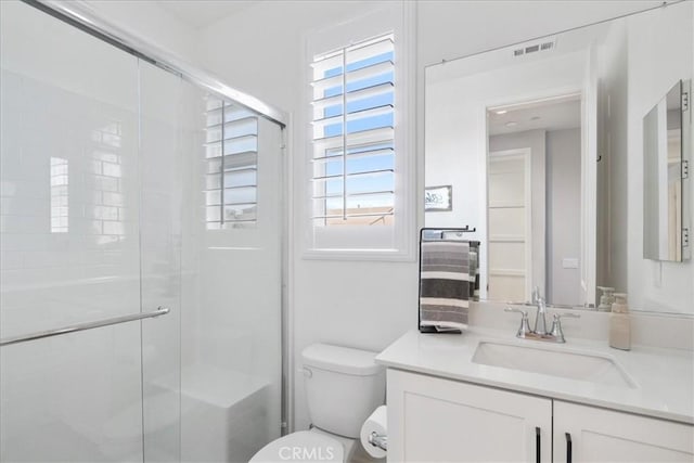 bathroom featuring visible vents, vanity, a shower stall, and toilet