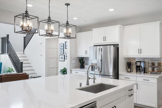 kitchen with open floor plan, stainless steel refrigerator with ice dispenser, a sink, and decorative light fixtures