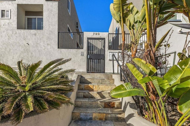 entrance to property featuring a gate, fence, and stucco siding