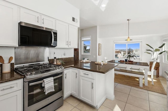 kitchen with light tile patterned flooring, stainless steel appliances, a peninsula, visible vents, and white cabinets