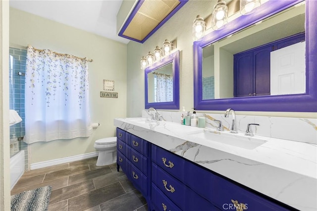 bathroom featuring baseboards, a sink, toilet, and double vanity