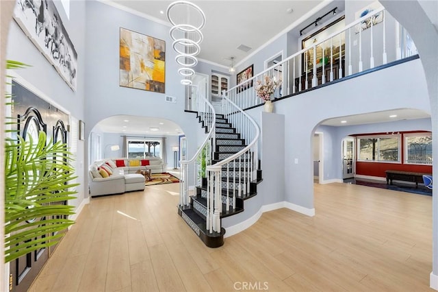 entryway featuring arched walkways, crown molding, and wood finished floors