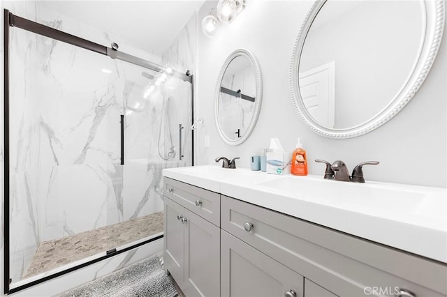 full bathroom featuring a sink, a marble finish shower, and double vanity