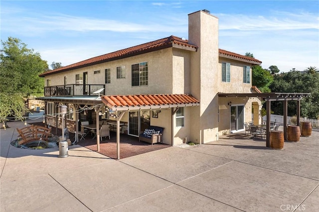 back of property featuring a tile roof, a patio, a chimney, stucco siding, and a pergola