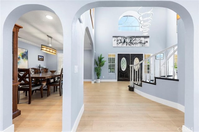 foyer entrance with a healthy amount of sunlight, stairs, baseboards, and wood finished floors