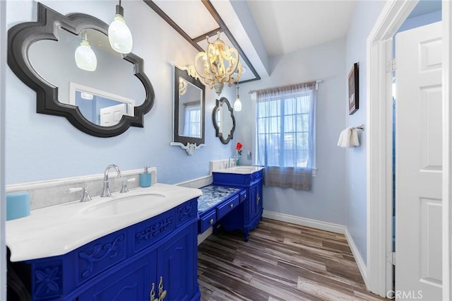 bathroom featuring an inviting chandelier, baseboards, wood finished floors, and vanity