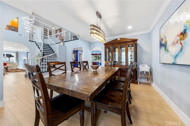 dining room with visible vents, arched walkways, baseboards, ornamental molding, and stairs