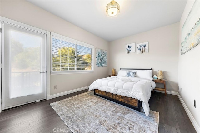 bedroom featuring access to exterior, baseboards, and dark wood-type flooring