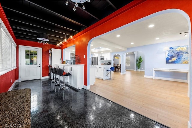 interior space with arched walkways, beamed ceiling, baseboards, and recessed lighting