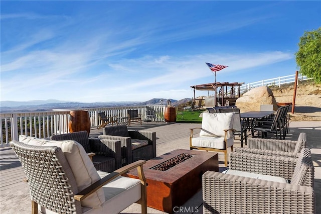 view of patio with outdoor dining space, an outdoor living space with a fire pit, and a deck with mountain view