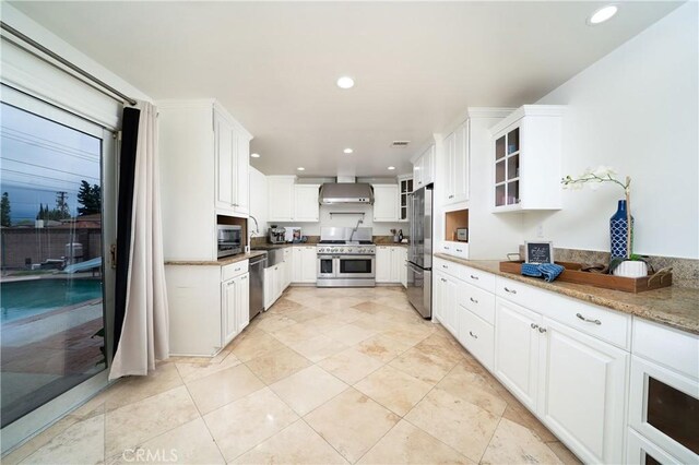 kitchen with glass insert cabinets, white cabinets, stainless steel appliances, and wall chimney exhaust hood