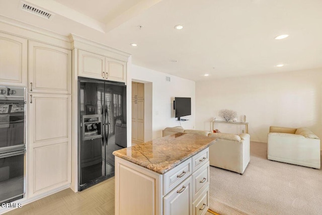 kitchen with open floor plan, light stone counters, black refrigerator with ice dispenser, and visible vents