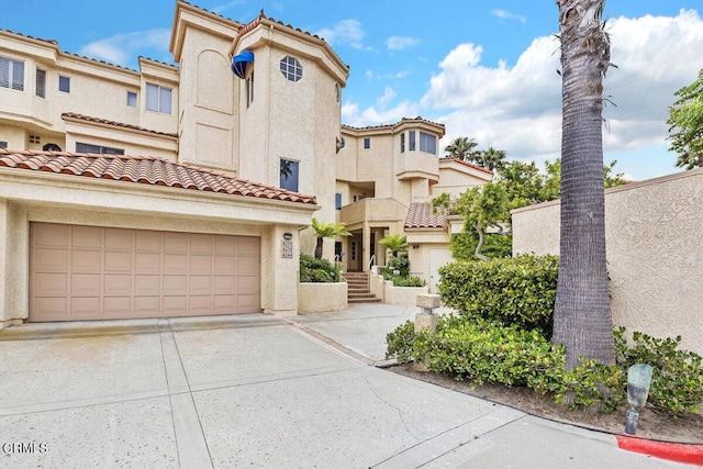 mediterranean / spanish-style house with a tile roof, driveway, and stucco siding