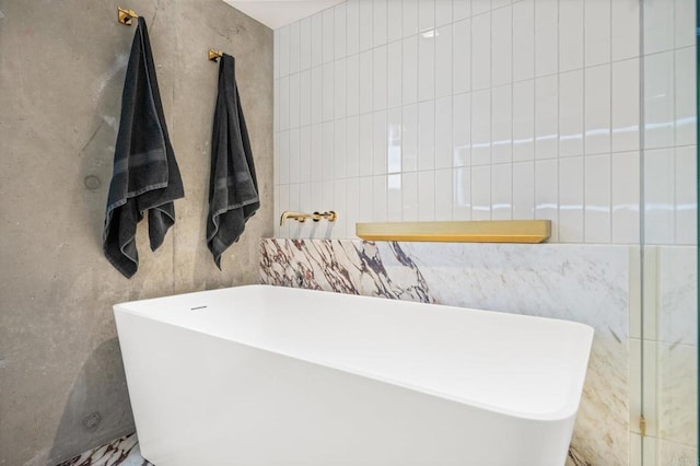 bathroom featuring tile walls and a freestanding bath