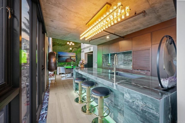 kitchen with stone countertops, a sink, and light wood-style flooring