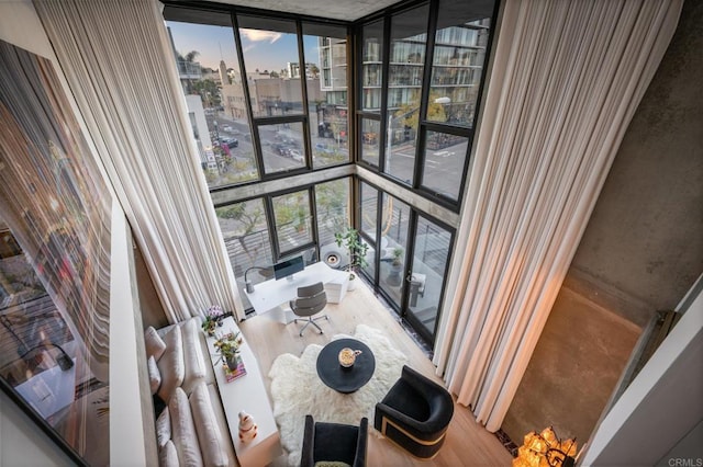 interior space with a view of city, a wall of windows, and wood finished floors