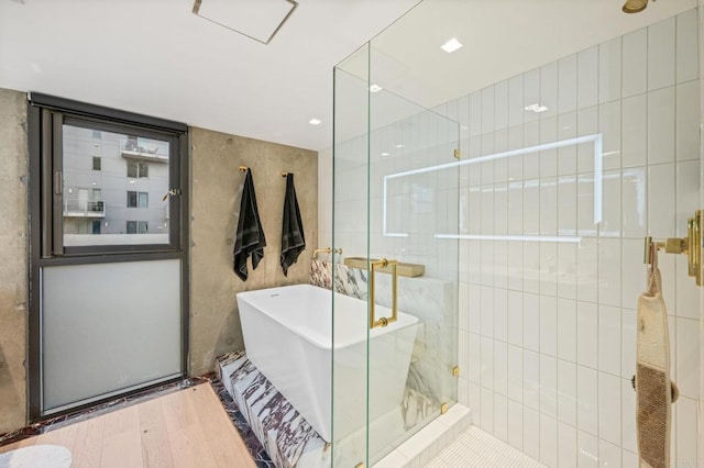 bathroom featuring a stall shower, a soaking tub, wood finished floors, and tile walls