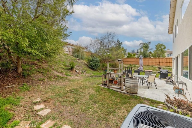 view of yard with a fenced backyard, central AC unit, and a patio