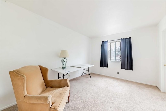 living area featuring light carpet and baseboards