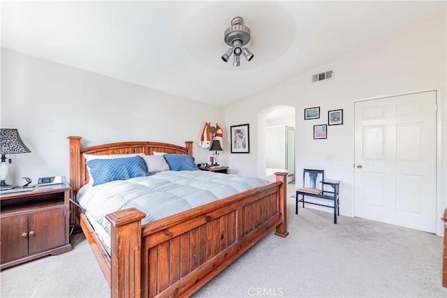 bedroom with light colored carpet, arched walkways, visible vents, and a ceiling fan