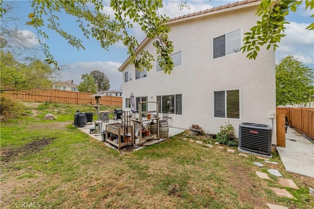 rear view of property with cooling unit, a fenced backyard, a yard, and stucco siding