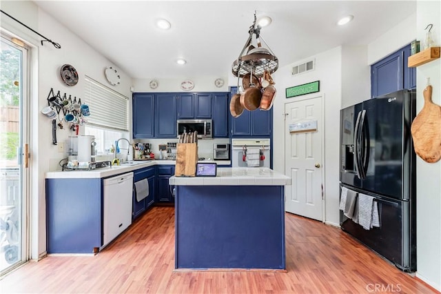 kitchen featuring white appliances, visible vents, blue cabinetry, and tile counters