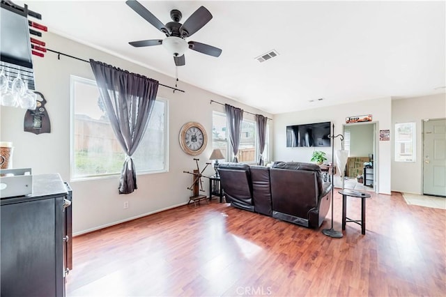 living area with ceiling fan, visible vents, and wood finished floors