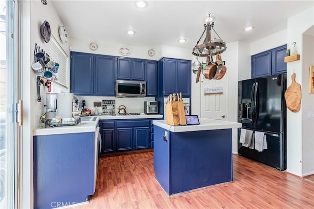 kitchen featuring blue cabinetry, stainless steel microwave, and black fridge with ice dispenser