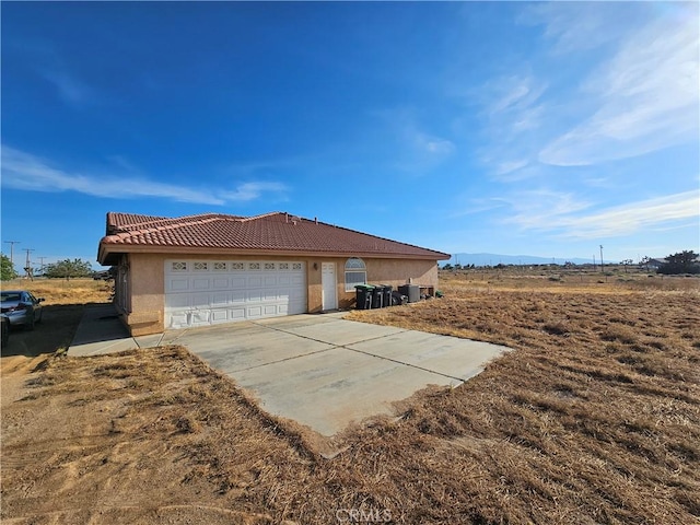 view of front of home featuring driveway, a tiled roof, a garage, and stucco siding