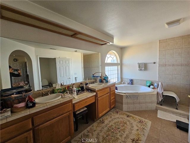 bathroom featuring tile patterned flooring, a sink, visible vents, a bath, and double vanity