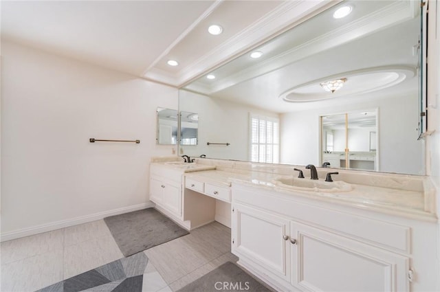 bathroom with crown molding, a sink, baseboards, and double vanity