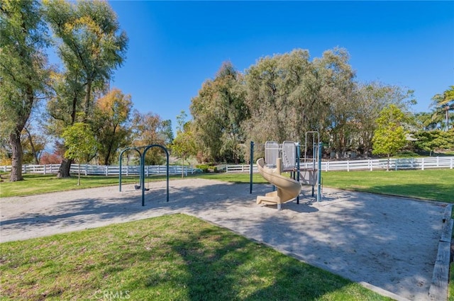 view of community featuring a yard, playground community, and fence