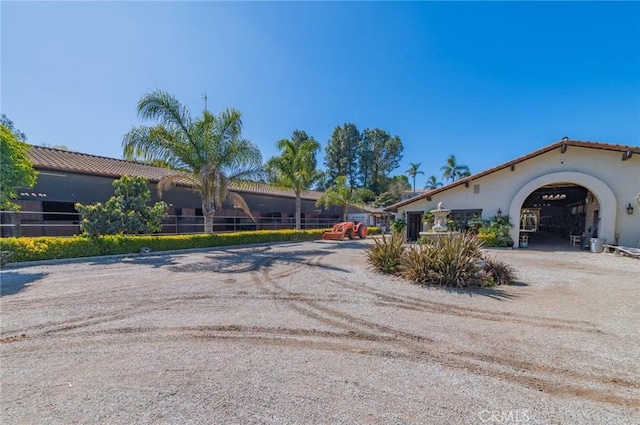 view of home's exterior featuring dirt driveway, a tile roof, and stucco siding