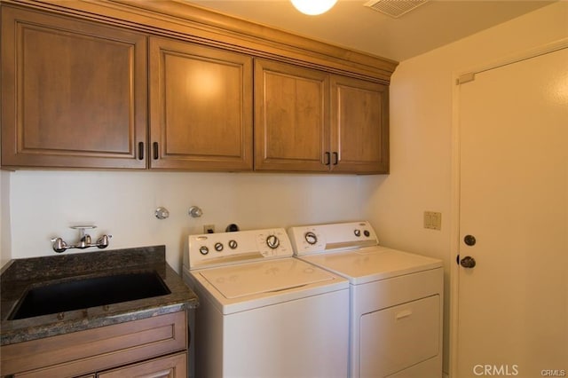 clothes washing area with cabinet space, visible vents, a sink, and washer and dryer