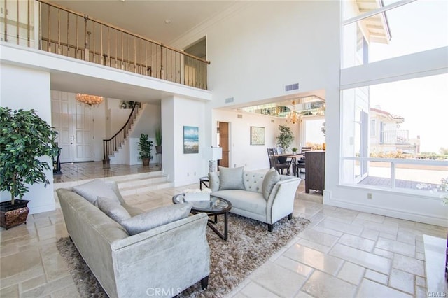 living room with a notable chandelier, visible vents, baseboards, stairway, and stone tile flooring