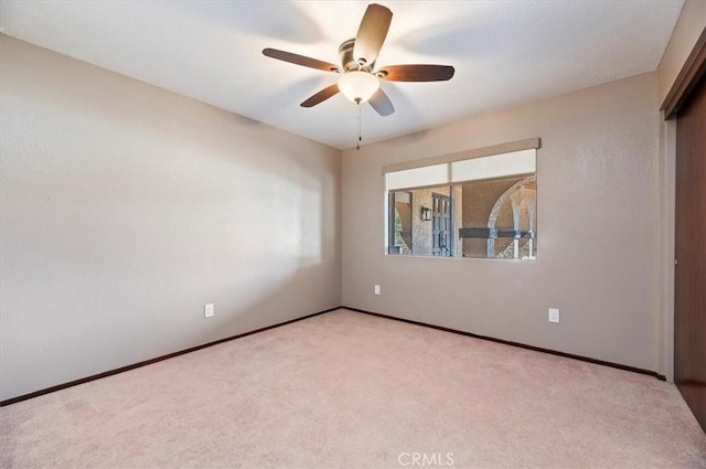 empty room featuring light carpet, ceiling fan, and baseboards