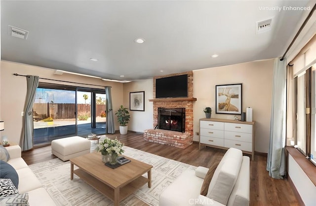 living room with a fireplace, wood finished floors, and visible vents