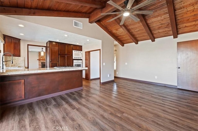 kitchen featuring ceiling fan, lofted ceiling with beams, white appliances, dark wood-style flooring, and a sink