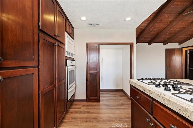 kitchen with white appliances, visible vents, a textured ceiling, light wood-type flooring, and a warming drawer